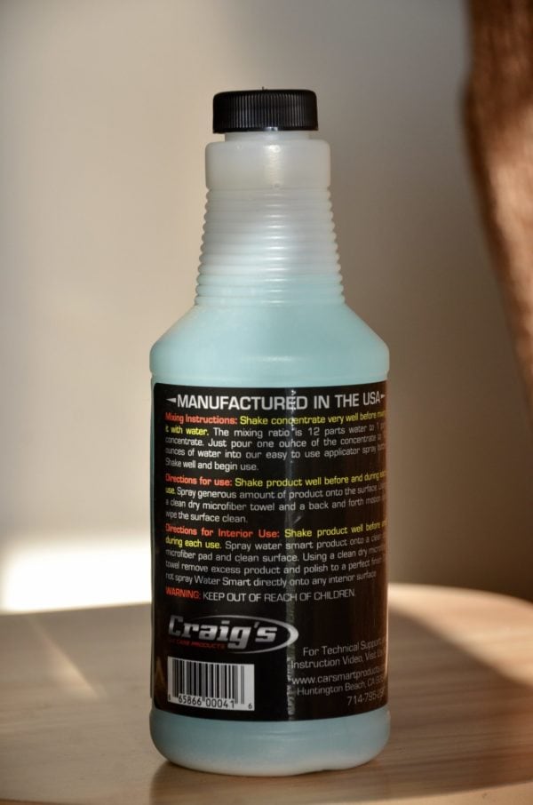 A bottle of Craig’s Waterless Wash & Wax Alternative for Drought sits on a wooden surface. The label includes mixing instructions, usage information, and a warning to keep out of reach of children. The bottle features a black cap and branding that reads "craig's"—a perfect wax alternative for drought conditions.