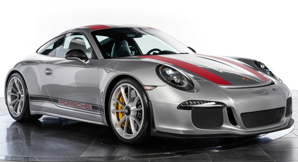 A sleek, silver Porsche 911 sports car with red racing stripes on the hood and roof. The car features aerodynamic design, prominent alloy wheels, and the Porsche logo on the front. REVIVIfy Coatings enhances its glossy finish as it’s photographed in a well-lit studio setting on a reflective surface.