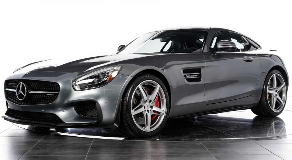 A sleek, silver Mercedes-Benz AMG GT coupe is displayed in a well-lit showroom. The car features a glossy finish, prominent front grille, aggressive styling, and red brake calipers visible through the alloy wheels.