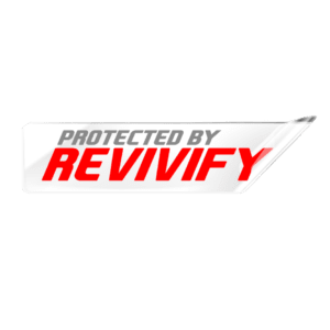 A "Protected By Revivify" clear vinyl sticker, measuring 2 inches, showcases a design with gray text reading "PROTECTED BY" and bold red text stating "REVIVIFY." It features a white background with a red border and slight shadowing. The top right corner of the sticker is curled, and it is shown on a pink surface.