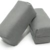 Two gray, rectangular Applicator Pads for car seat belts are shown. The pads appear to be made of soft fabric, providing cushioning for comfort during car rides. They are positioned diagonally against each other.