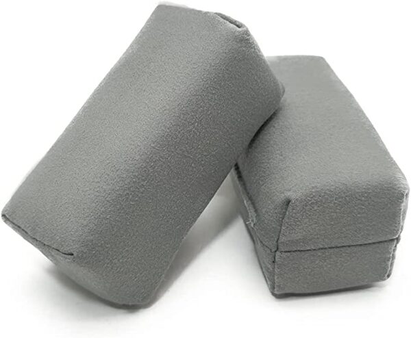 Two gray, rectangular Applicator Pads for car seat belts are shown. The pads appear to be made of soft fabric, providing cushioning for comfort during car rides. They are positioned diagonally against each other.